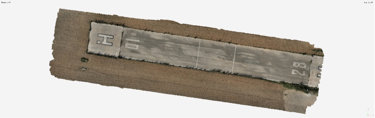 Aerial view of a rectangular concrete helipad with surrounding dirt, featuring helipad markings and faded lines