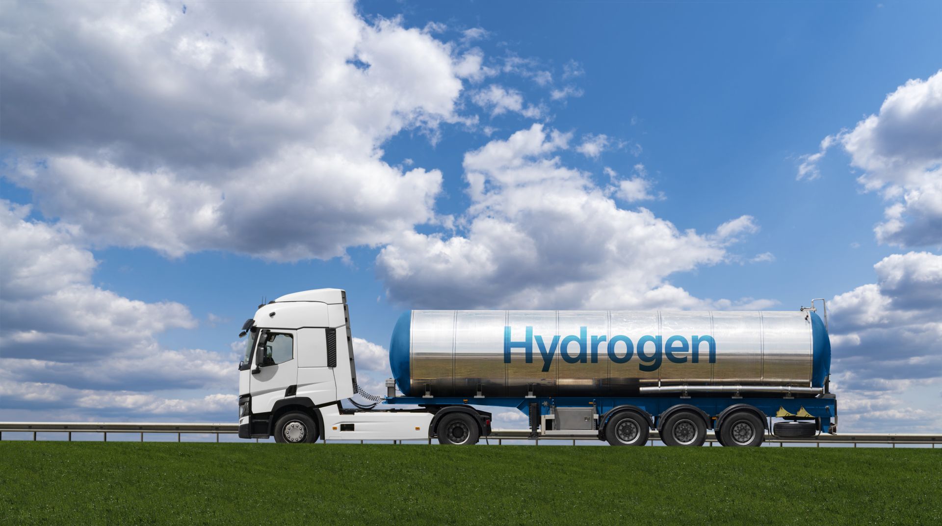Hydrogen tanker truck driving on a highway under a blue sky with clouds