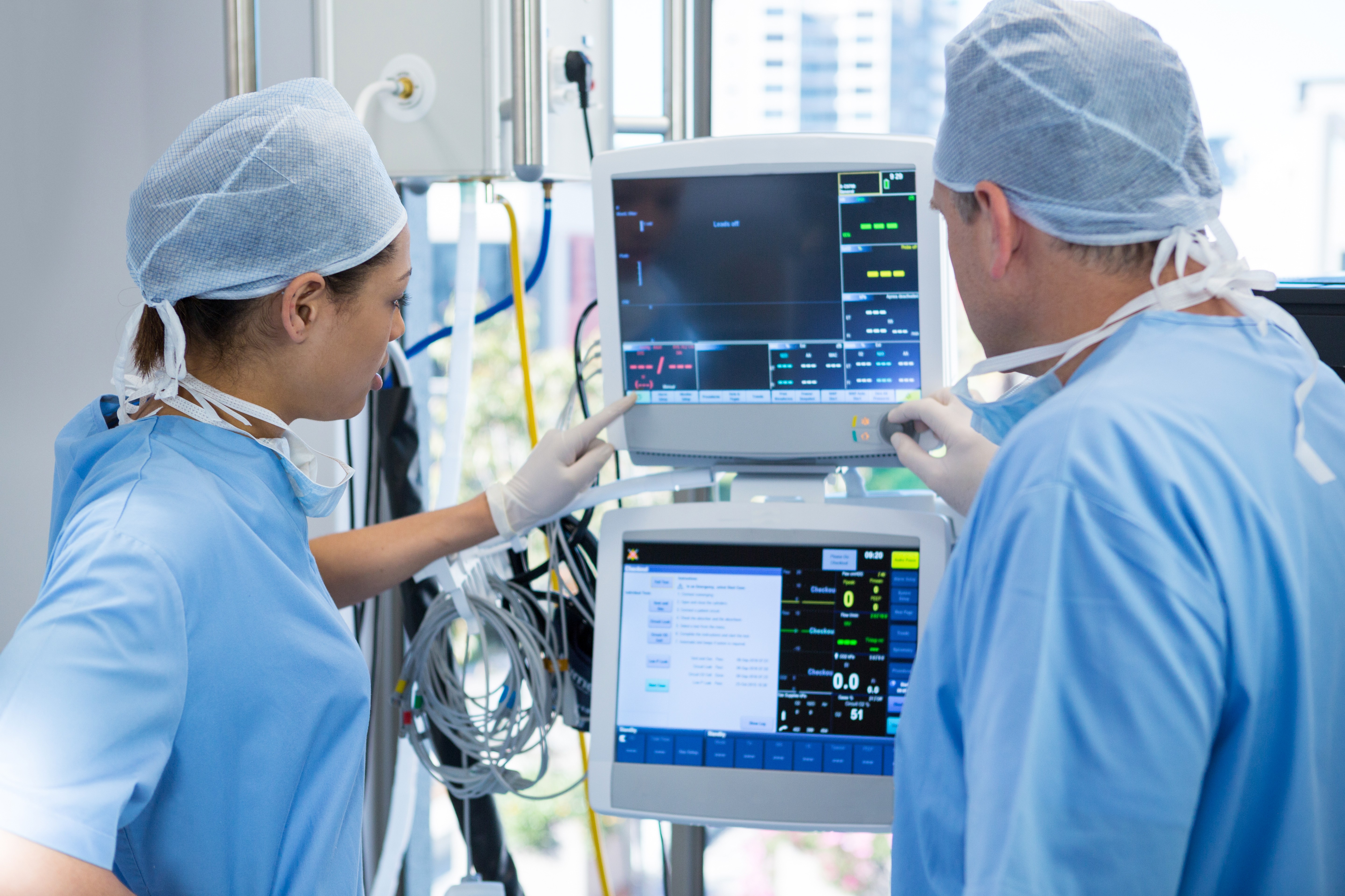 Doctors wearing white coats, intently reading information on a monitor