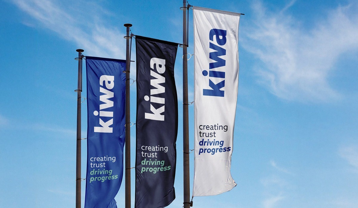 Three vertical Kiwa banners in blue, black, and white against a clear blue sky, each reading “creating trust driving progress.”