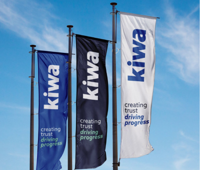 Tre Kiwi-flag vajer mod en blå himmel, med teksten “kiwa” og “creating trust driving progress”.